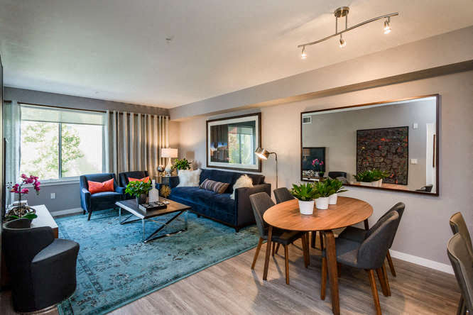 A living room with a blue rug and a wooden table.
