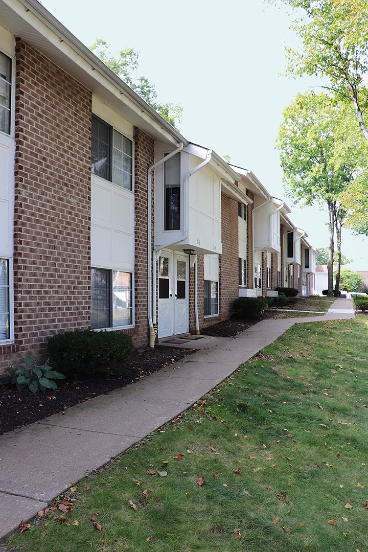 a sidewalk in front of a brick apartment building