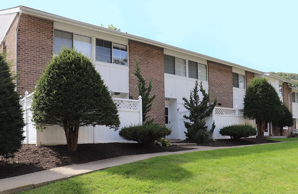 an apartment building with a lawn and trees in front of it
