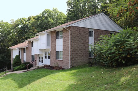 a white and brick house with a yard and trees