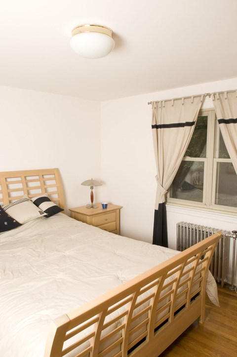 A bedroom with a bed, nightstand, and window.