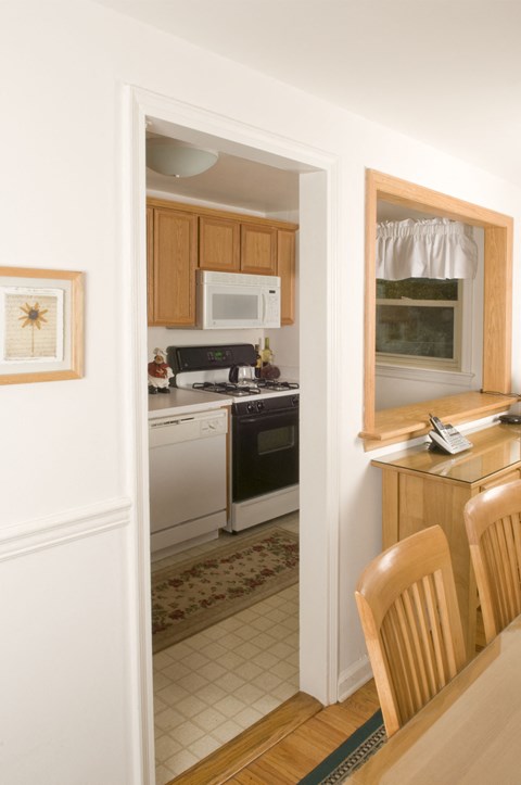 A kitchen with a white fridge and a microwave on top of it.