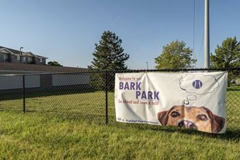 Fenced outdoor pet park labeled with signage reading 