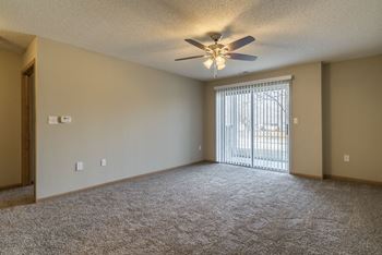 Empty living room with ceiling fan and sliding patio door