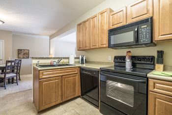 Corner of kitchen with black appliances looking into connected dining area