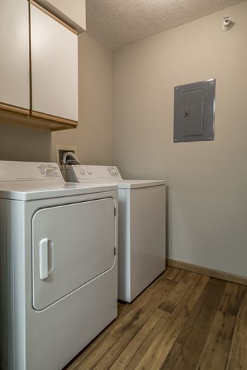 Full size washer and dryer side by side in laundry room with cabinet storage