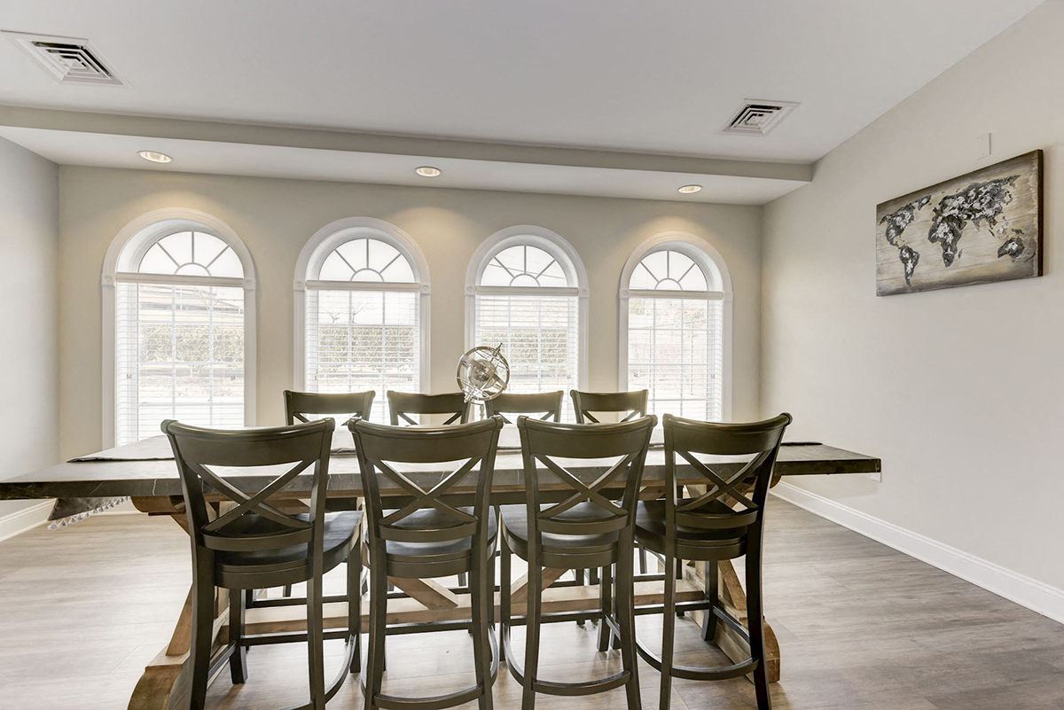 a dining room with a table and chairs and three windows