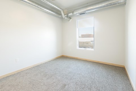 an empty room with a window and a carpeted floor