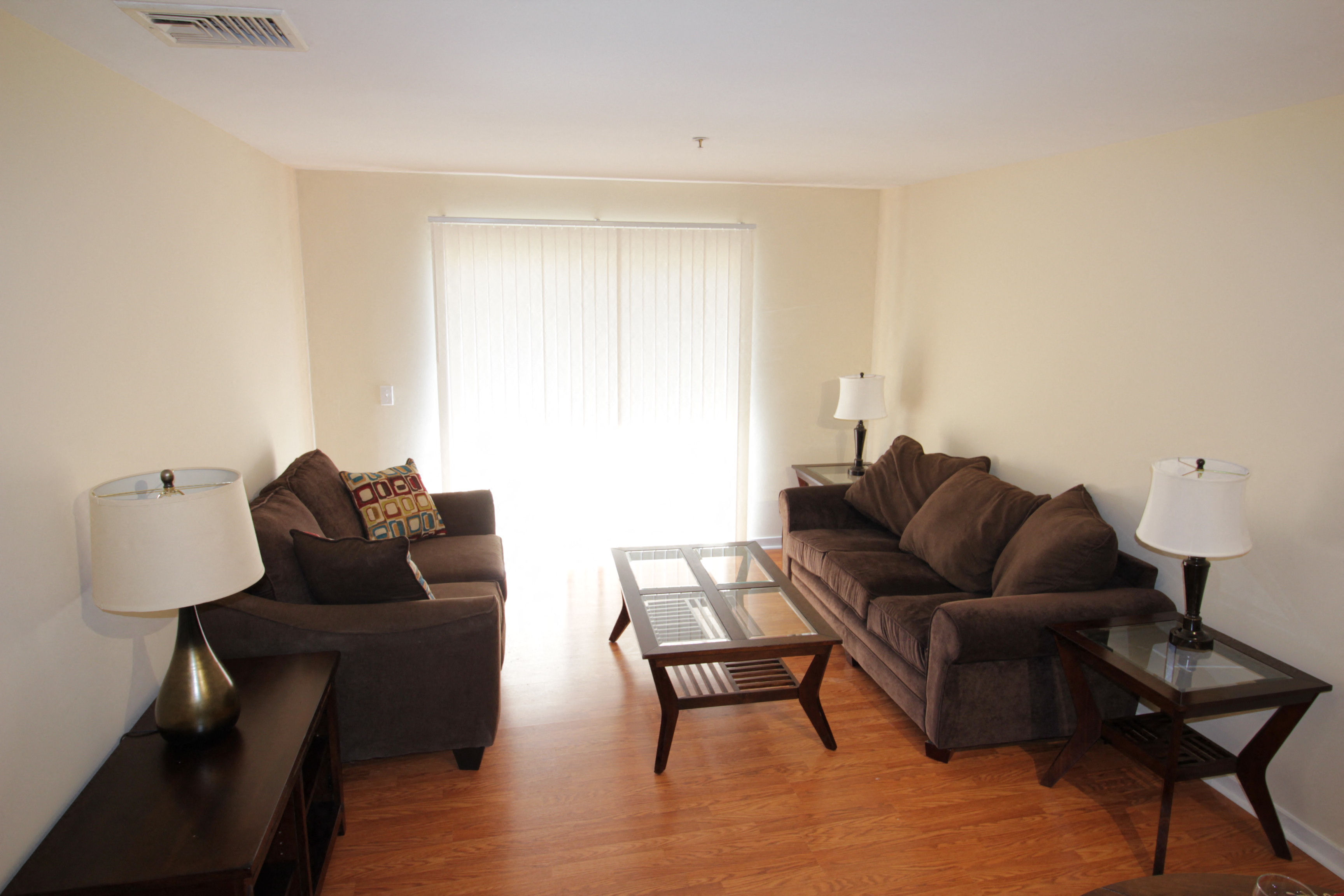 A living room with brown furniture and a glass table.