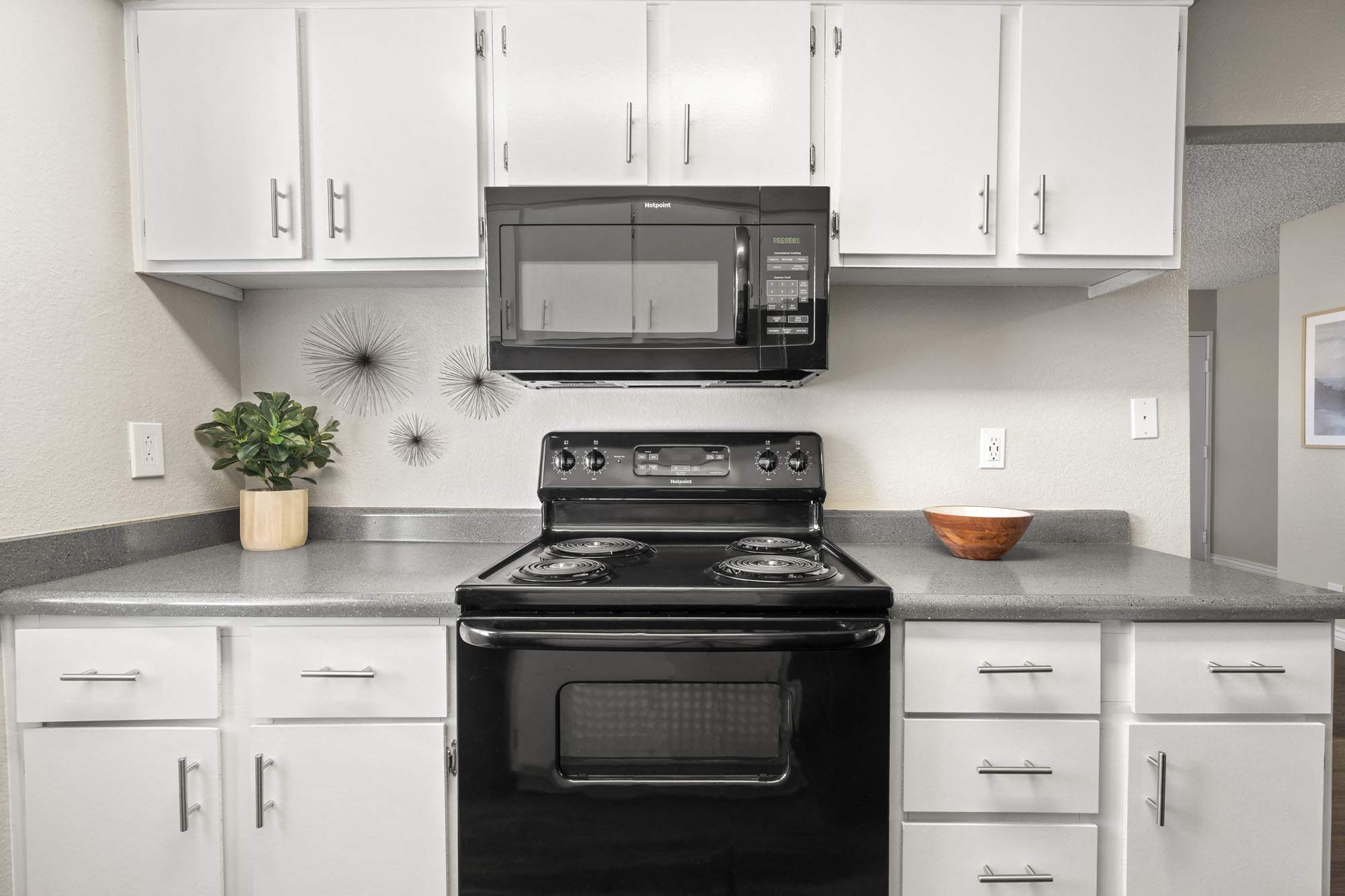 a kitchen with white cabinets and a black stove and microwave