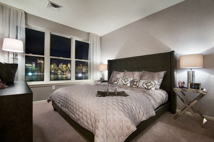 a bedroom with a large bed and a city at night