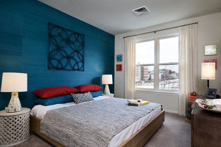 a bedroom with a bed and a blue wall and a window