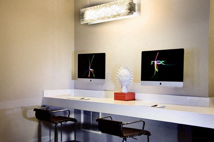 a desk with two monitors and chairs in a room