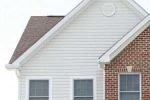 a brick house with white siding and a yard