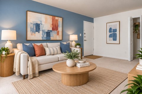 A living room with a white couch, a coffee table, and a painting on the wall.