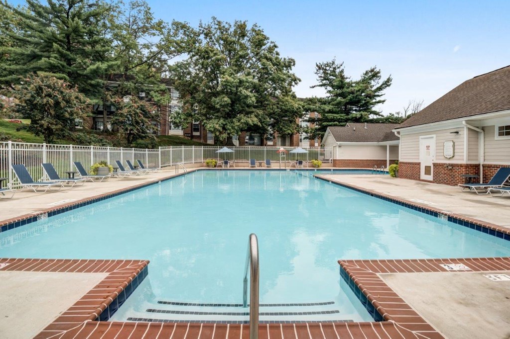 a swimming pool with chairs and a house in the background