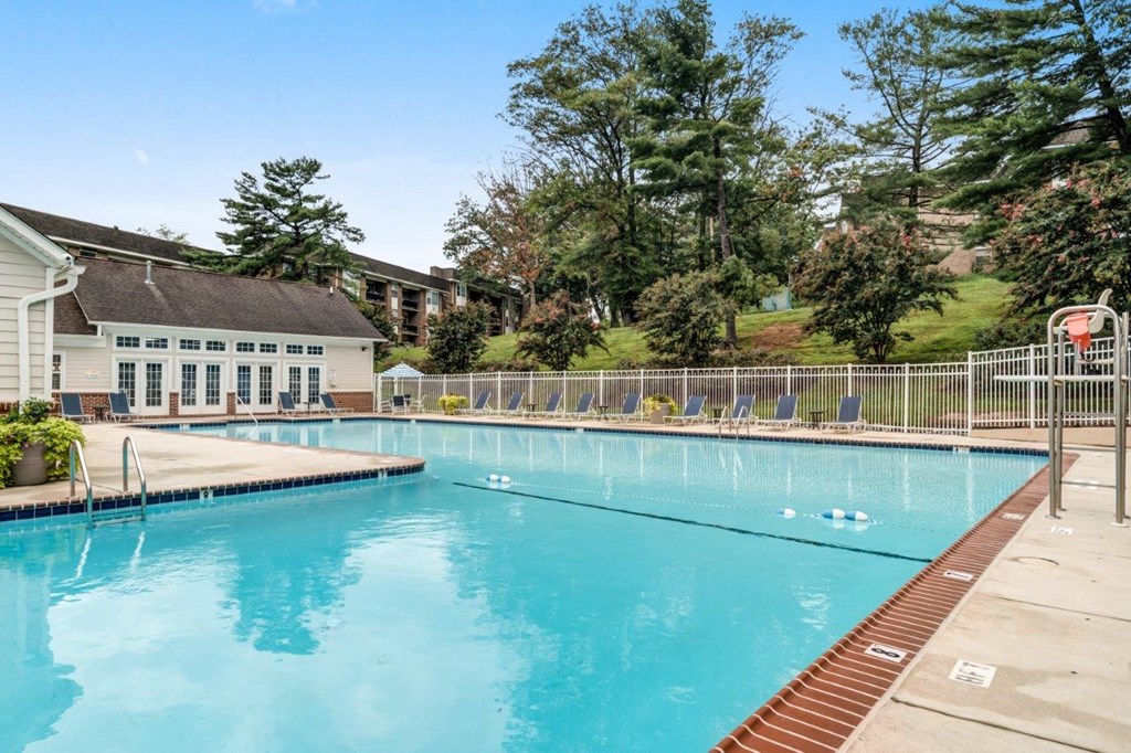 a swimming pool with a building and trees in the background