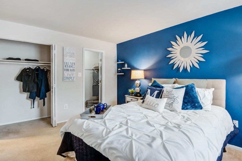 a bedroom with a blue accent wall and a white bed