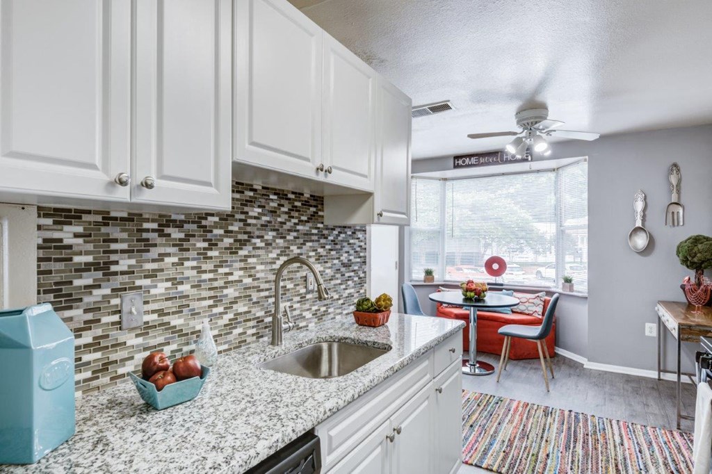 a kitchen with white cabinets and a sink and a window