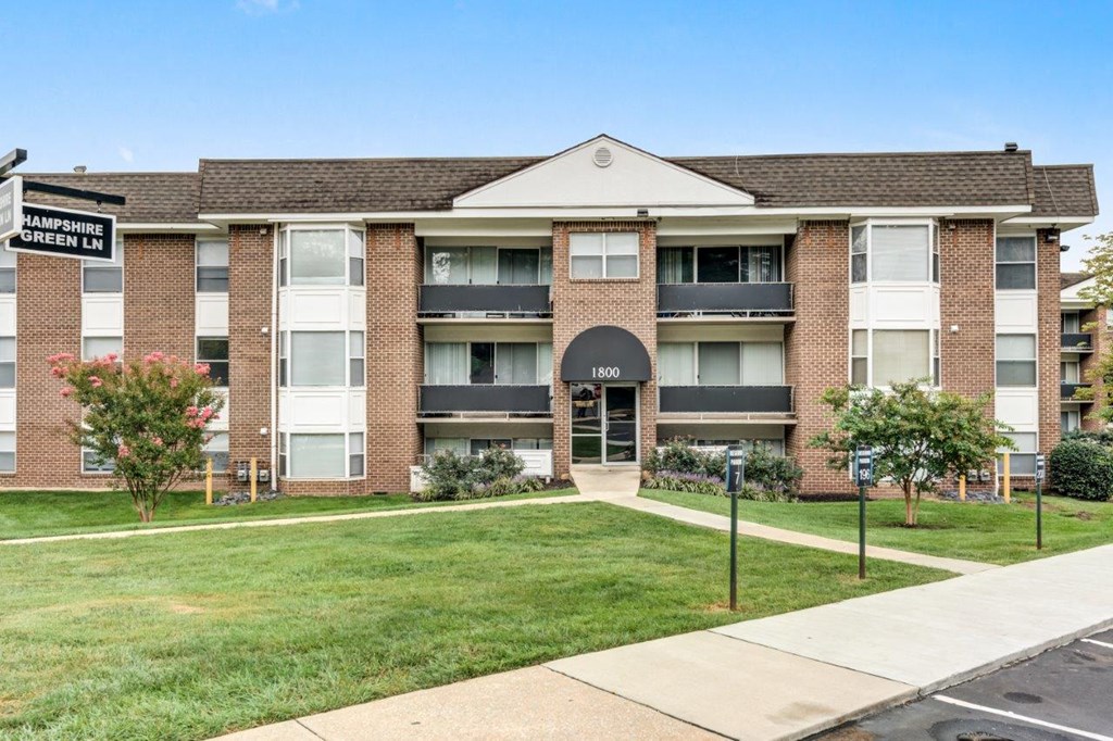 an apartment building with a sidewalk in front of it