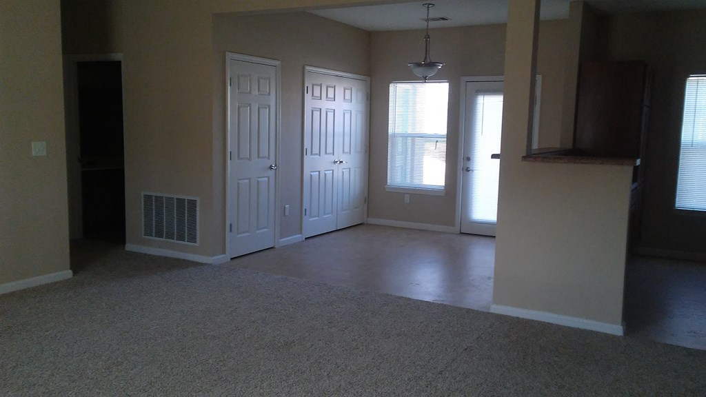an empty living room with two doors and a carpeted floor
