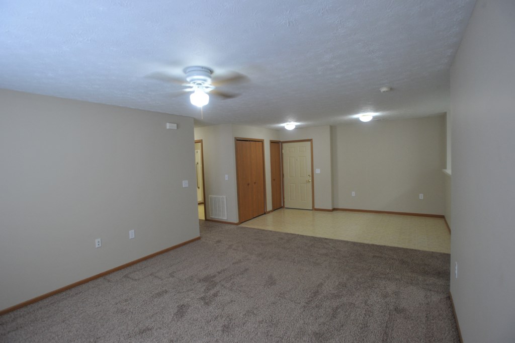 an empty living room with carpet and a ceiling fan
