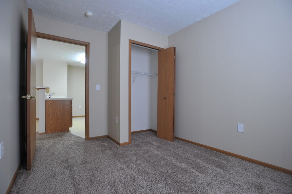 a bedroom with a carpeted floor and a door to a closet