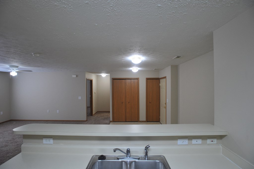 a kitchen with a sink and a counter in a empty room