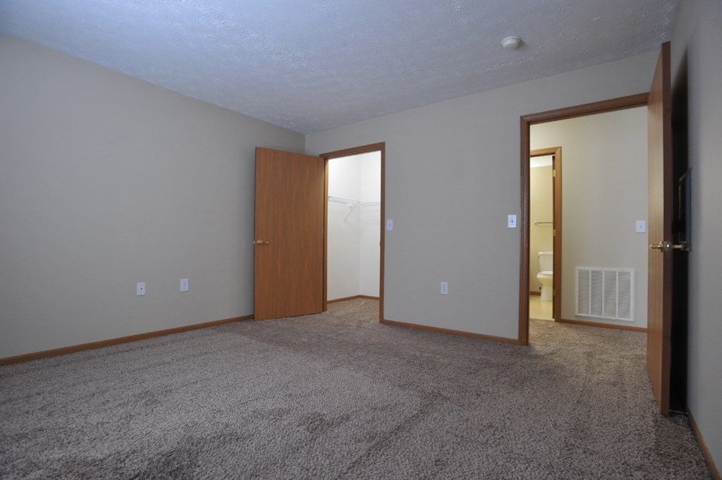 an empty living room with a door to a bathroom and a closet
