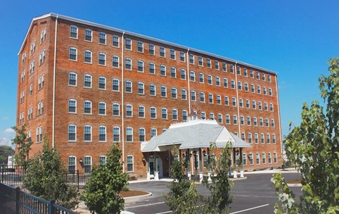 A large red brick building with a white roof and a black fence in front.