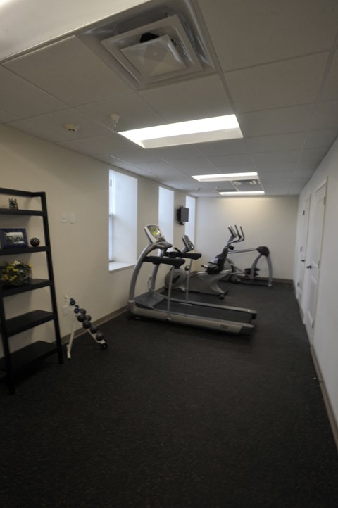 A gym room with a treadmill, elliptical trainer and weights.