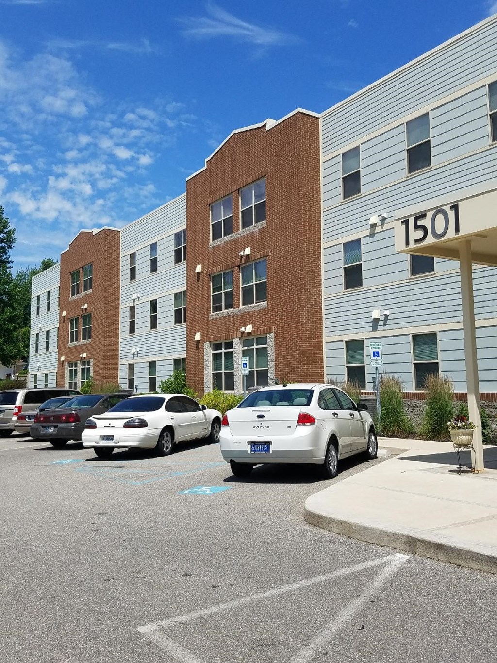a parking lot with cars in front of an apartment building