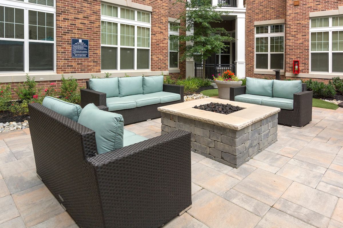 a patio with furniture and a fire pit in front of a building