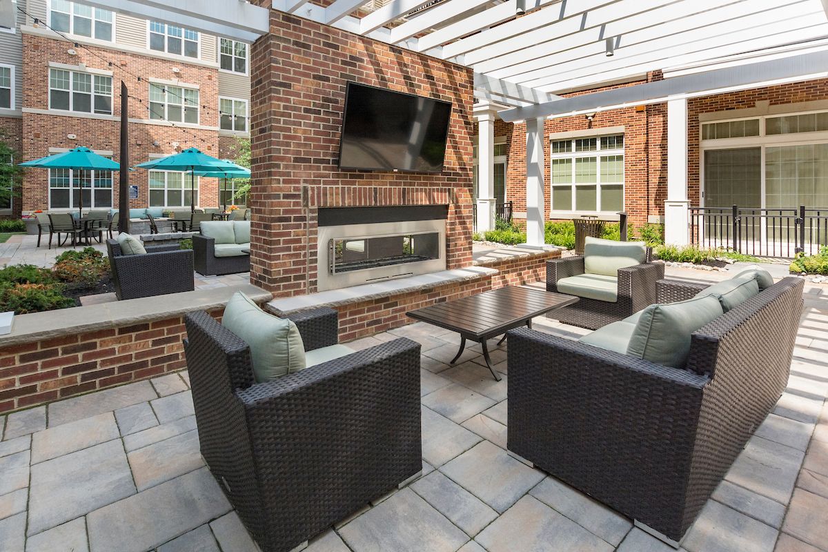 a patio with chairs and a television and a brick fireplace