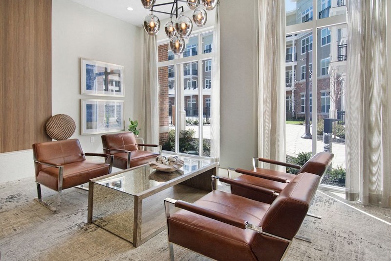 a living room with brown leather chairs and a glass table