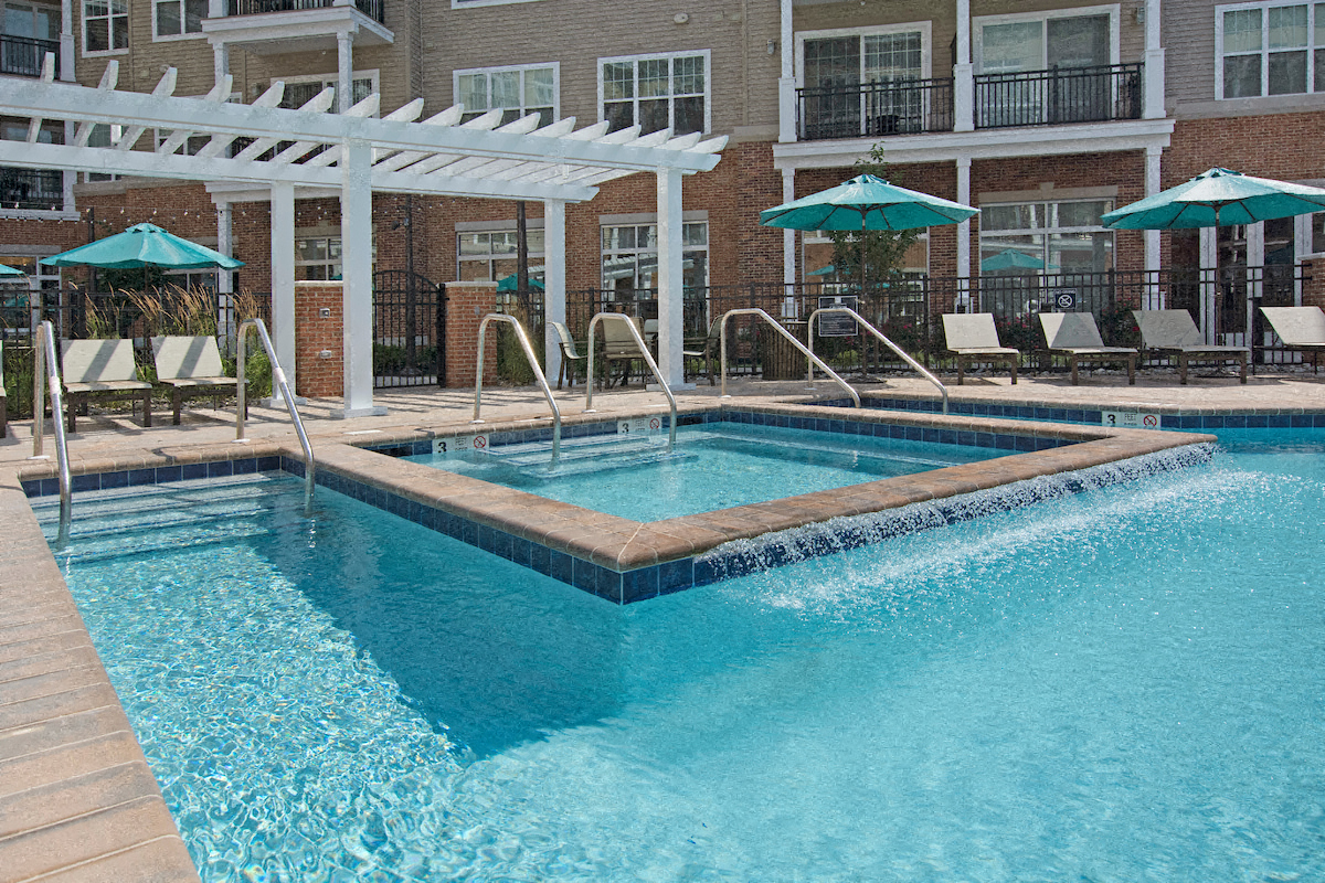 a swimming pool with umbrellas and chairs in front of a building