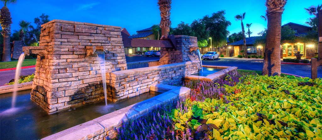 a water fountain in front of a house at night