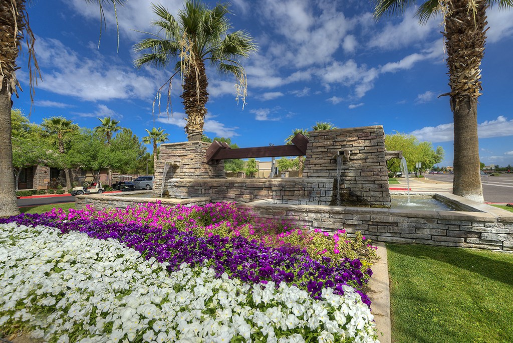 a stone fountain with flowers and palm trees