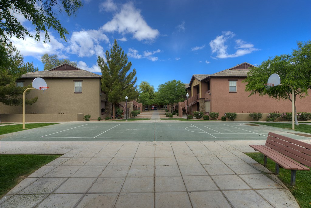 a tennis court between two buildings with a bench