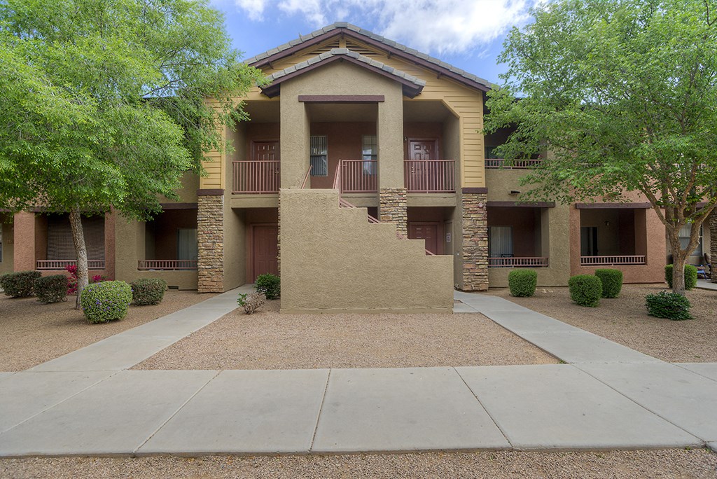 an exterior view of an apartment building with a sidewalk and trees