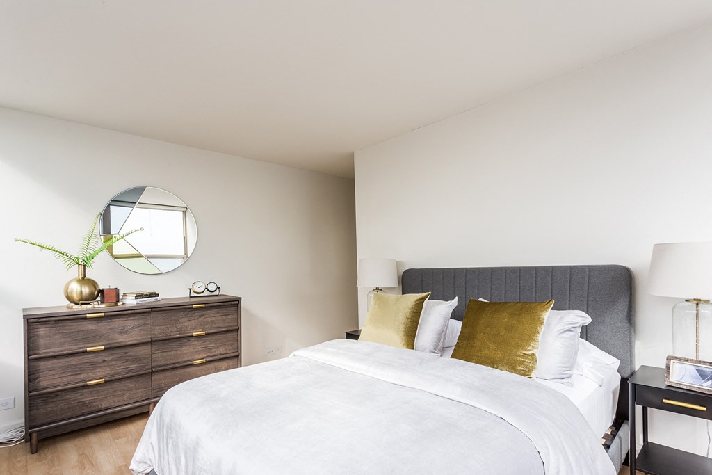 a bedroom with a bed and a dresser with a mirror