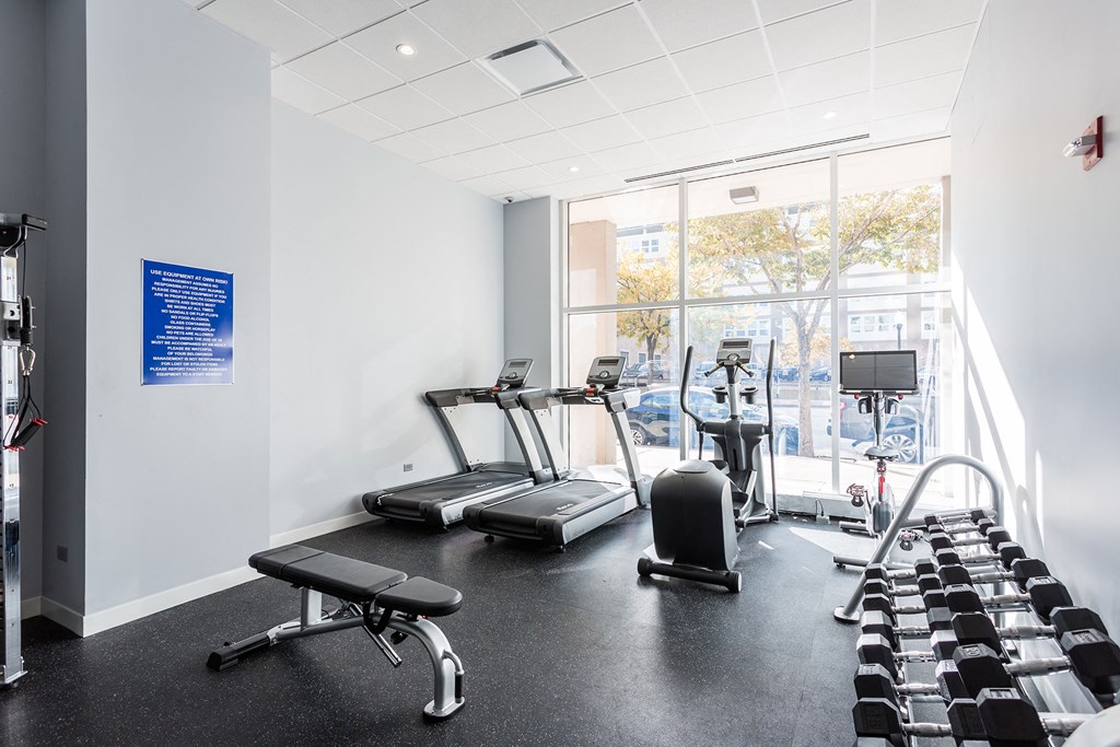 a gym with treadmills and other exercise equipment in a room with a window