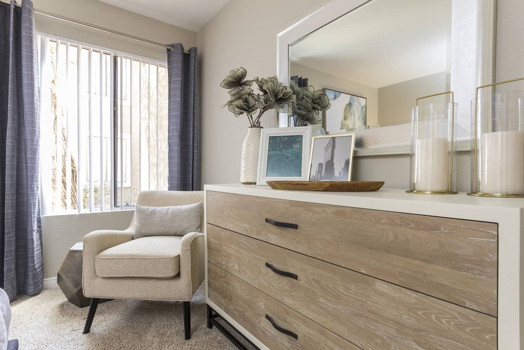 a bedroom with a dresser and a chair and a mirror