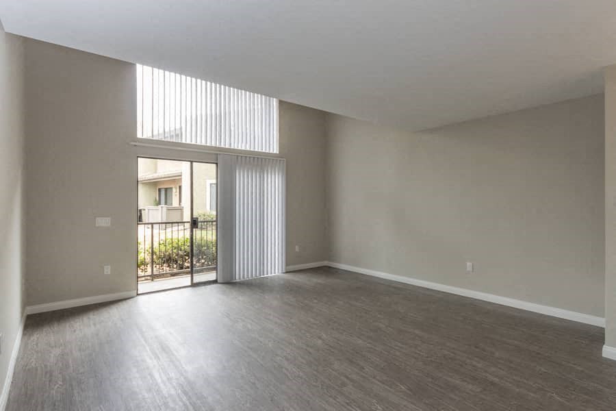 an empty living room with a door to a balcony