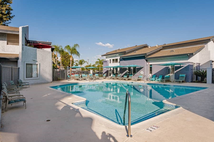 a large swimming pool with chairs and umbrellas