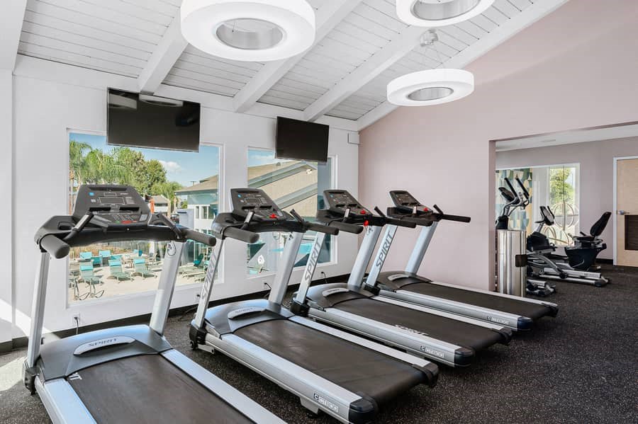 a gym with cardio equipment and a view of the pool