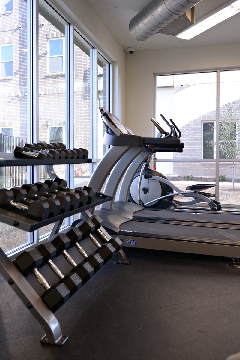a treadmill and weights in a gym with a large window