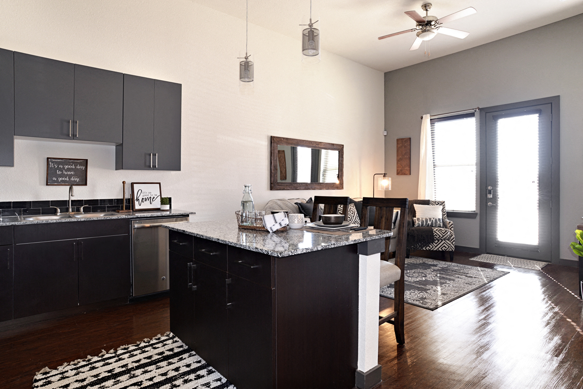 a kitchen with an island and a living room with a table and chairs
