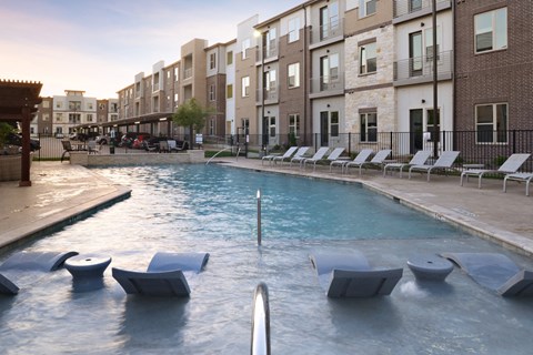 a large pool with chairs in front of a building