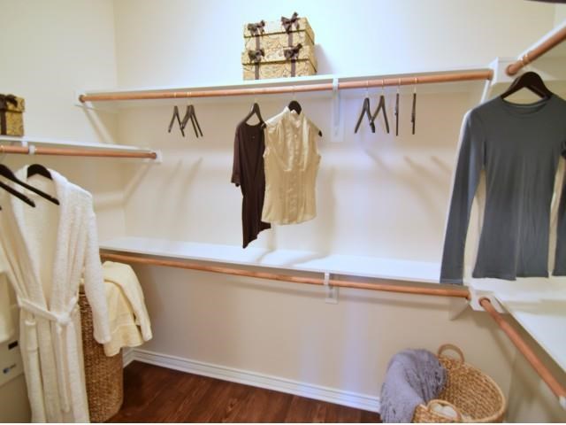 a walk in closet with clothes hanging on the wall